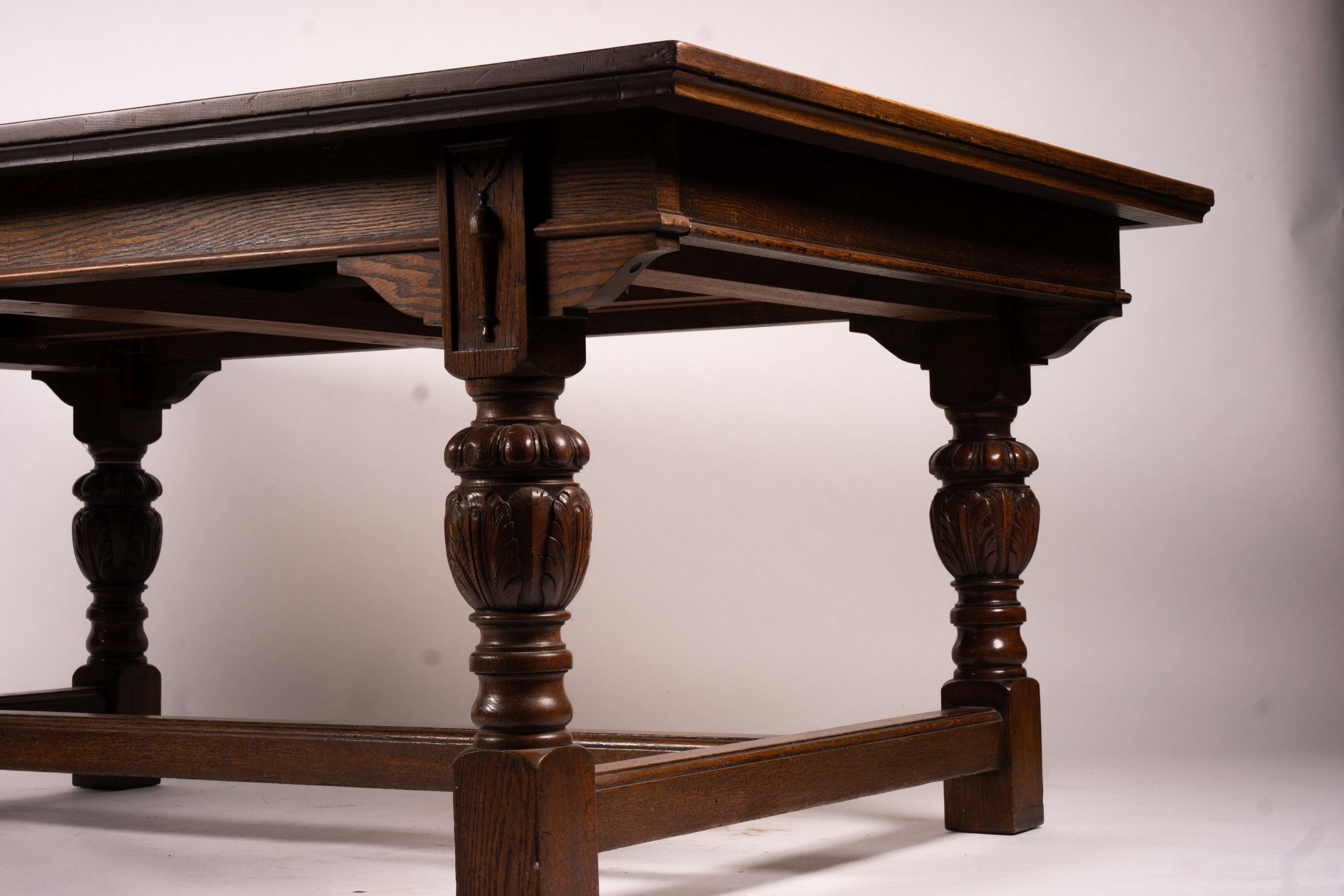 A 17th century style carved rectangular oak extending dining table with 'H' stretcher, 300cm extended, two spare leaves, width 121cm, height 75cm